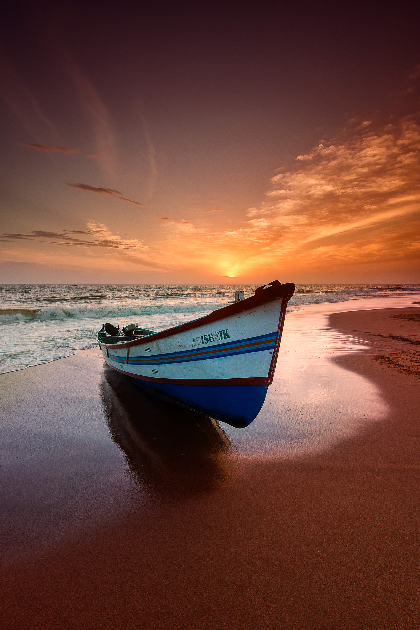 Fishing boat beached at sunset on golden shore