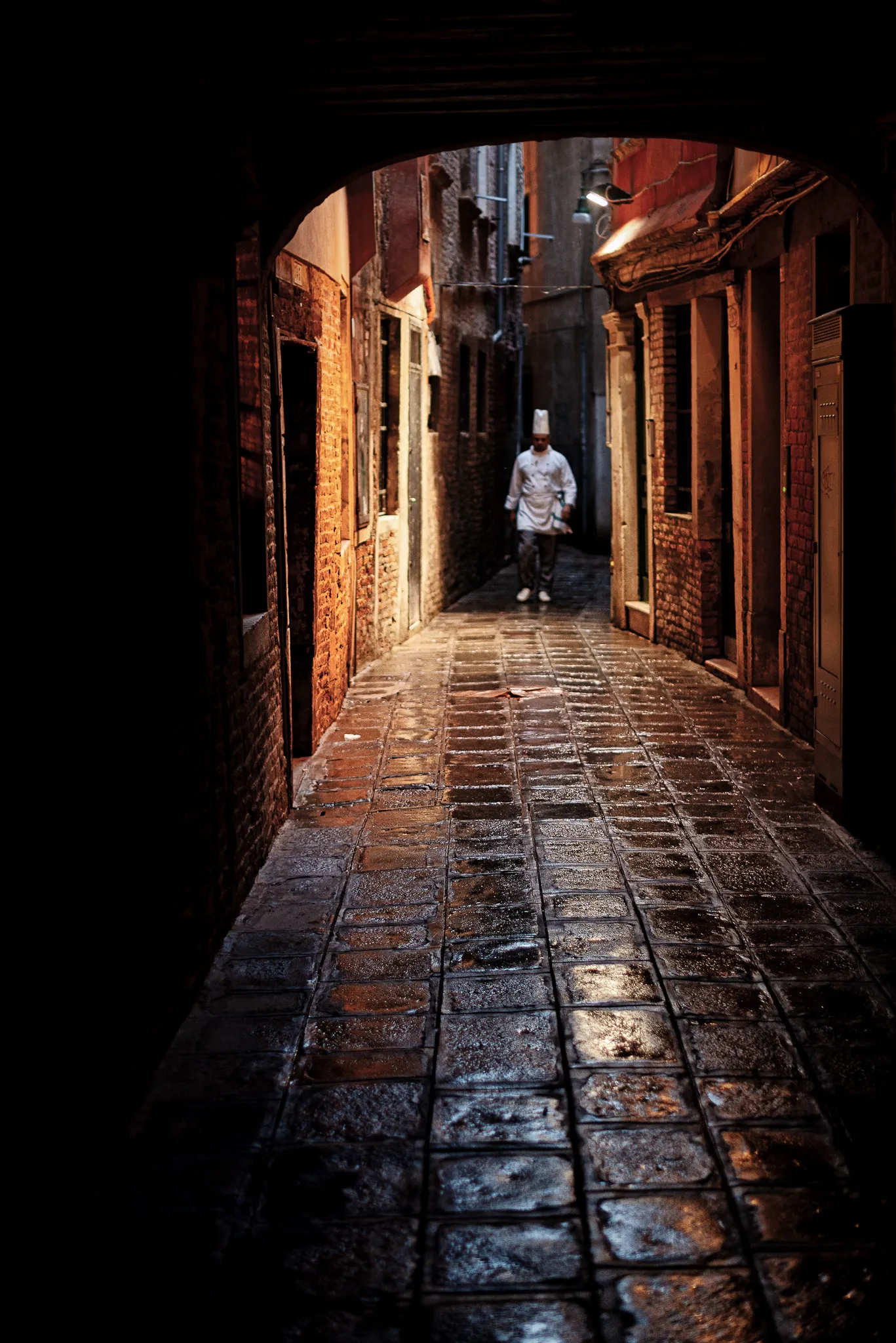 Red umbrella and wet cobblestone reflections in Venice at night