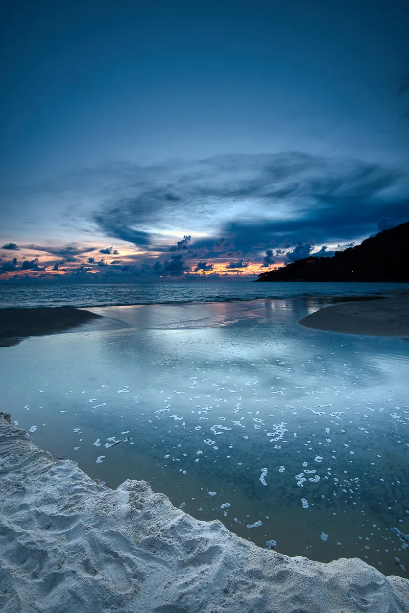 Sunset over water in Thailand with warm tones across sky and sea